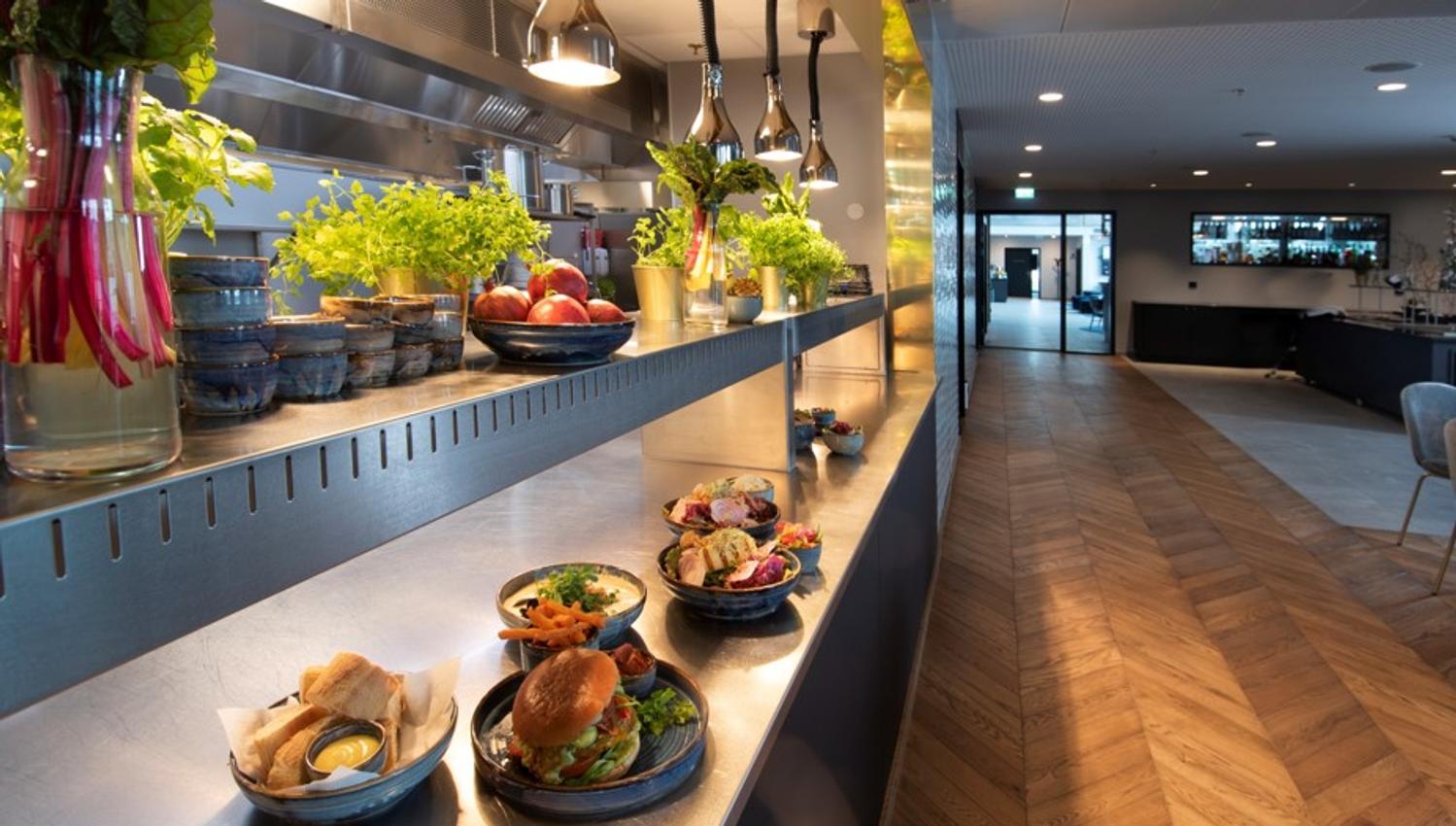 Mat fra Mandal Hotel, 4 forskjellige skåler. En med oppskåret bagett med noe gult å dyppe i. En med svær burger med masse grønt i + pommes frites. To med ulike salater.
Det er også fire små skåler med frukt