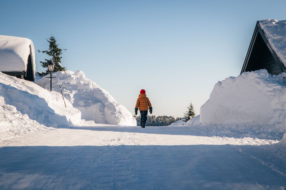 person går på en snødekt vei mellom hyttene på Lifjell Tunet i Bø
