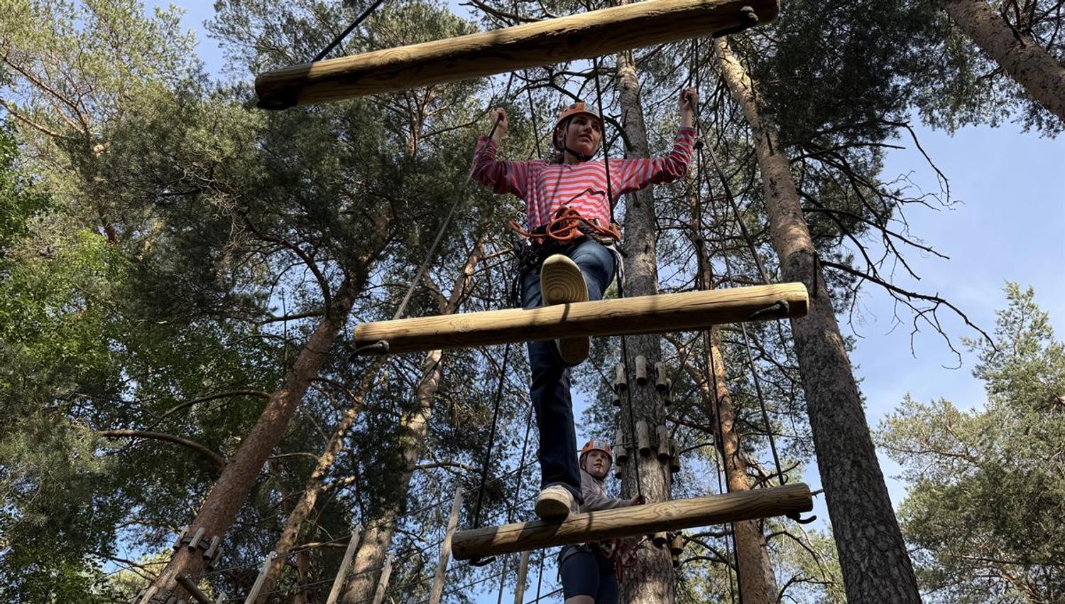 A participant climbing a vertical wooden ladder obstacle.