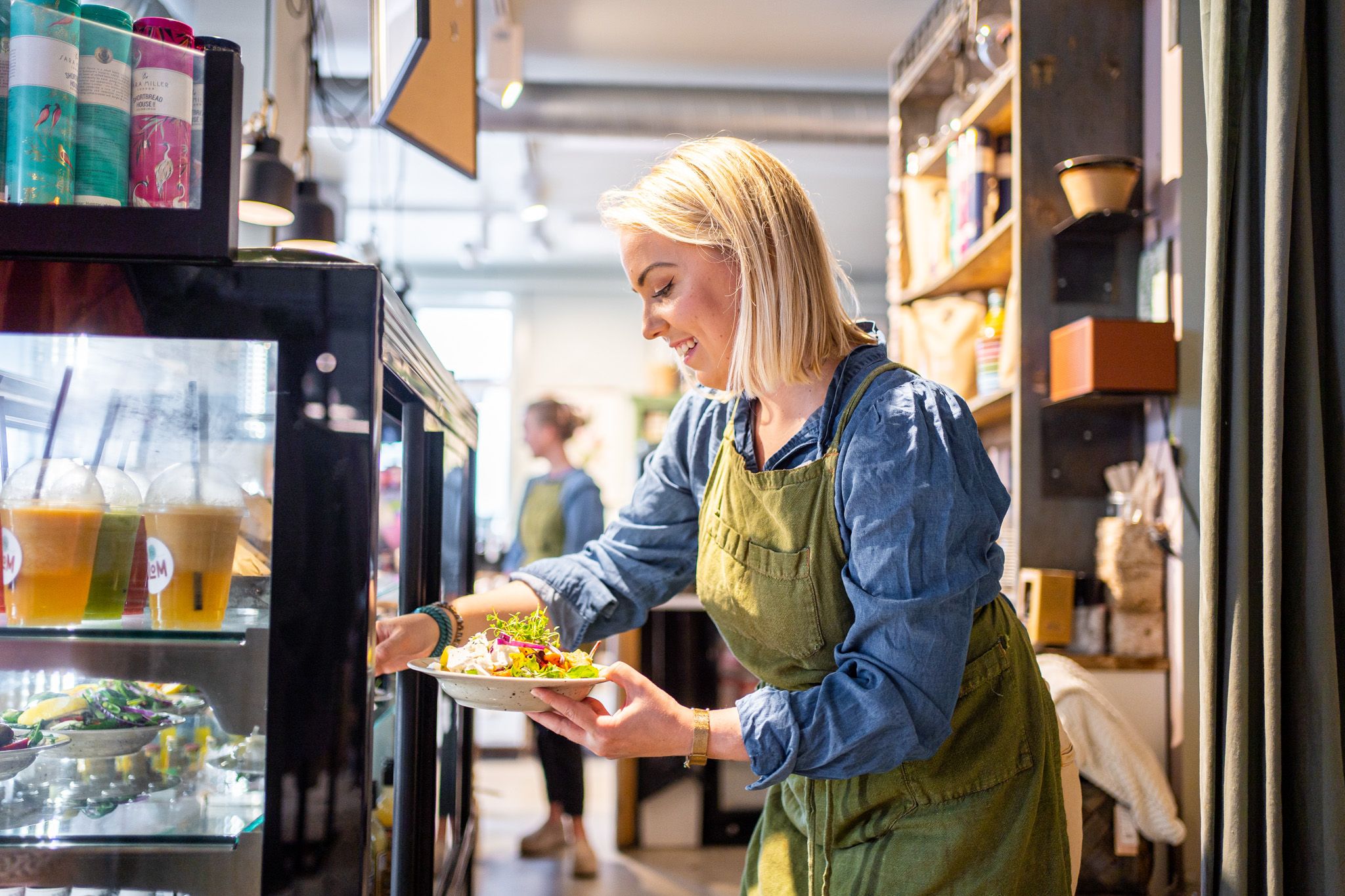 kvinne som henter ut en salat fra et kjøleskap