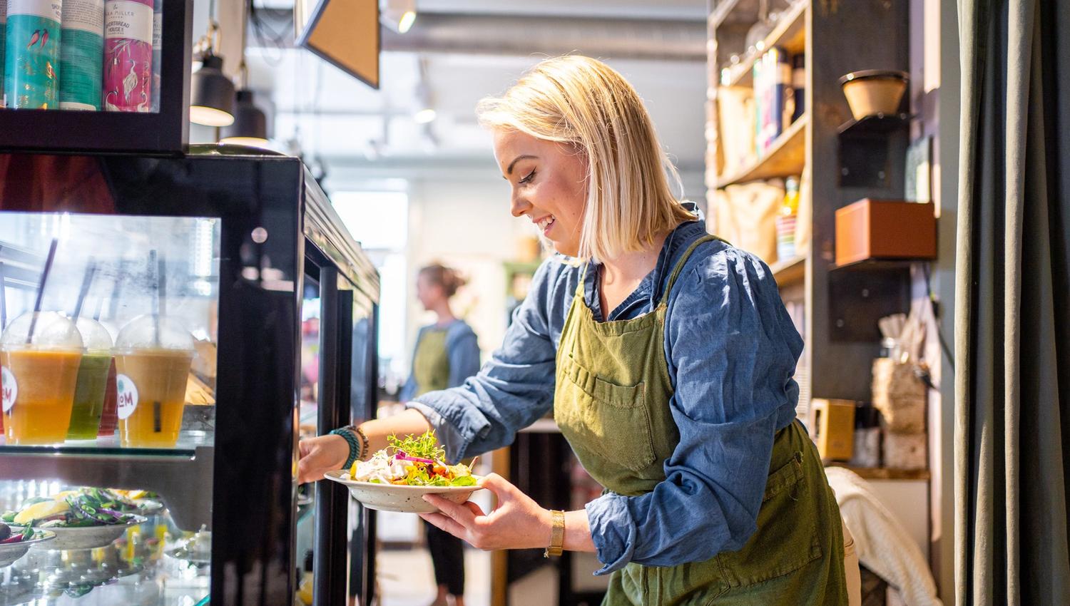 kvinne som henter ut en salat fra et kjøleskap