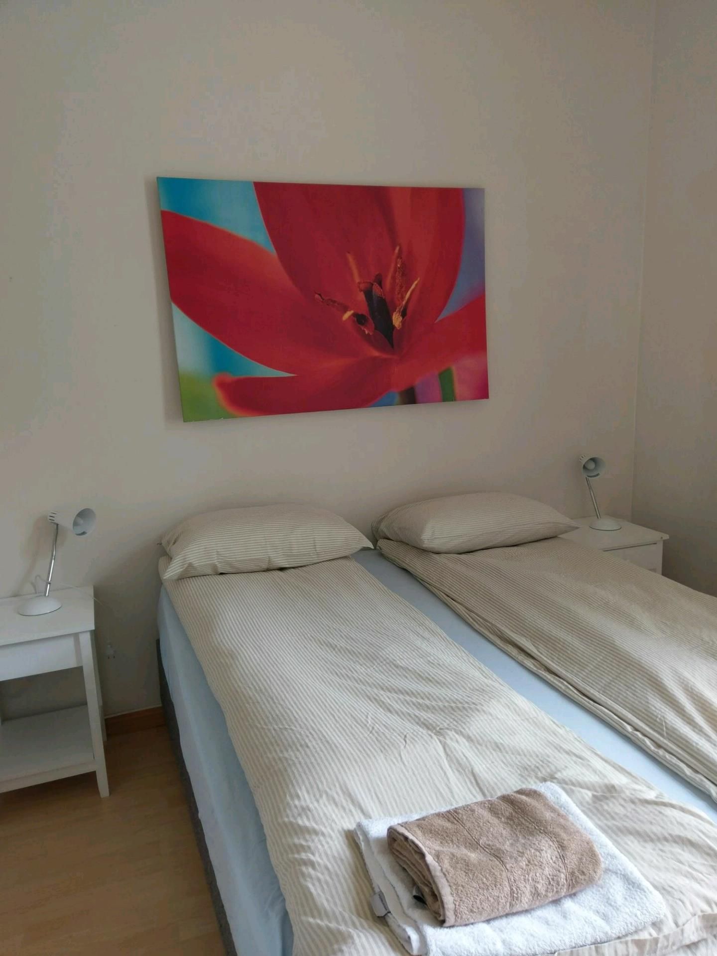 Lyst og komfortabelt soverom på Vikinghaug Apartments med to enkeltsenger og moderne kunst på veggen.