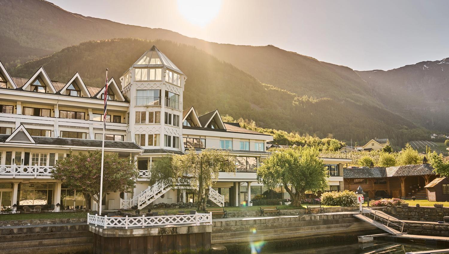 Hotel Ullensvang med hage og fjordutsikt i gyllen kveldssol – ein klassikar i Hardanger.