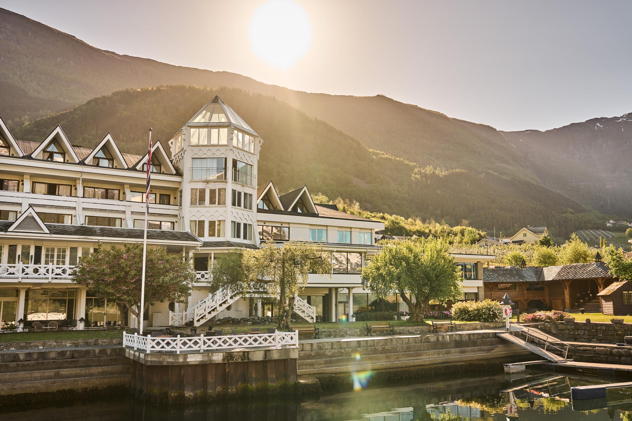 Hotel Ullensvang glowing in the golden evening light, surrounded by gardens and fjord views.