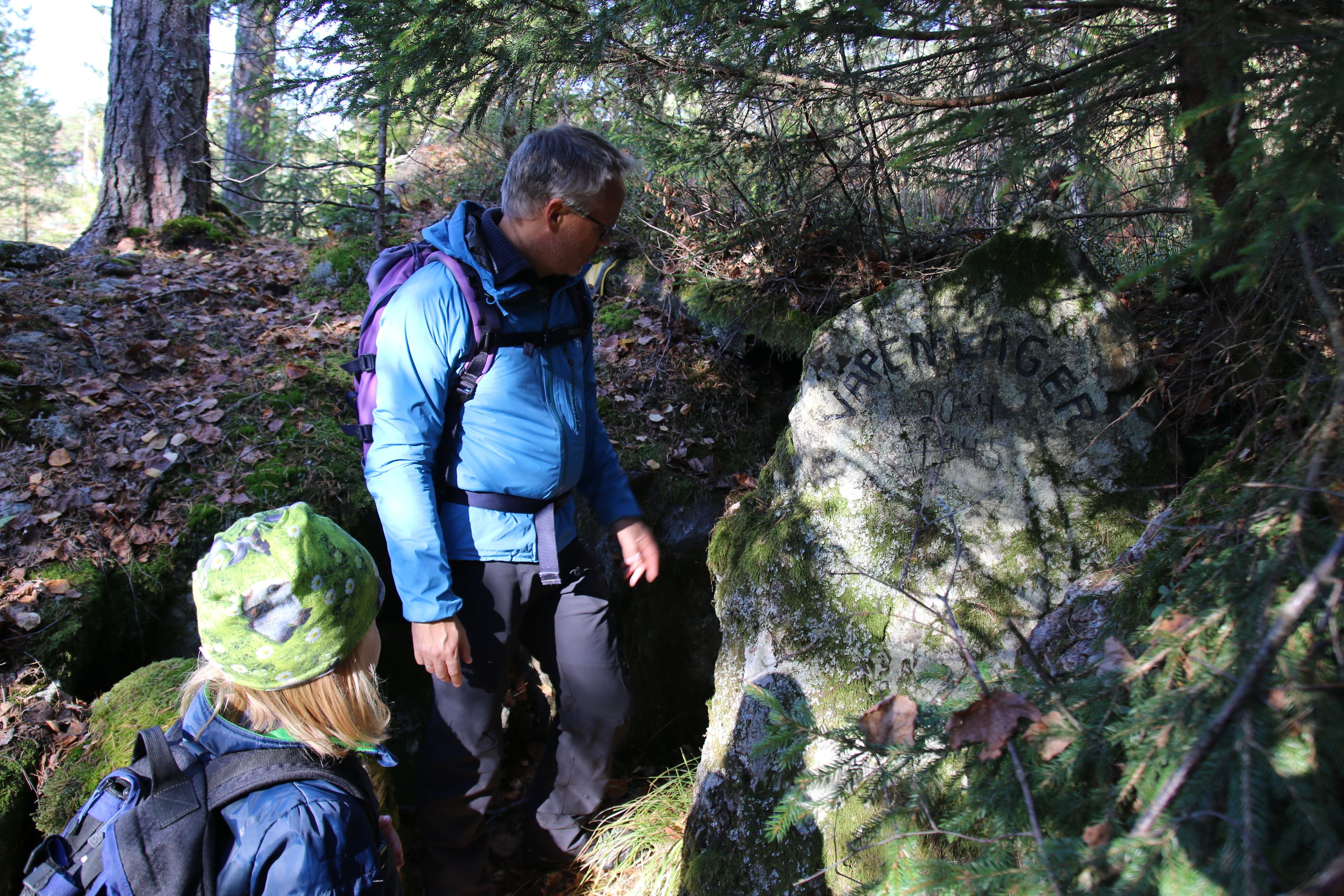 Voksen og barn ser på steinen med innskrift