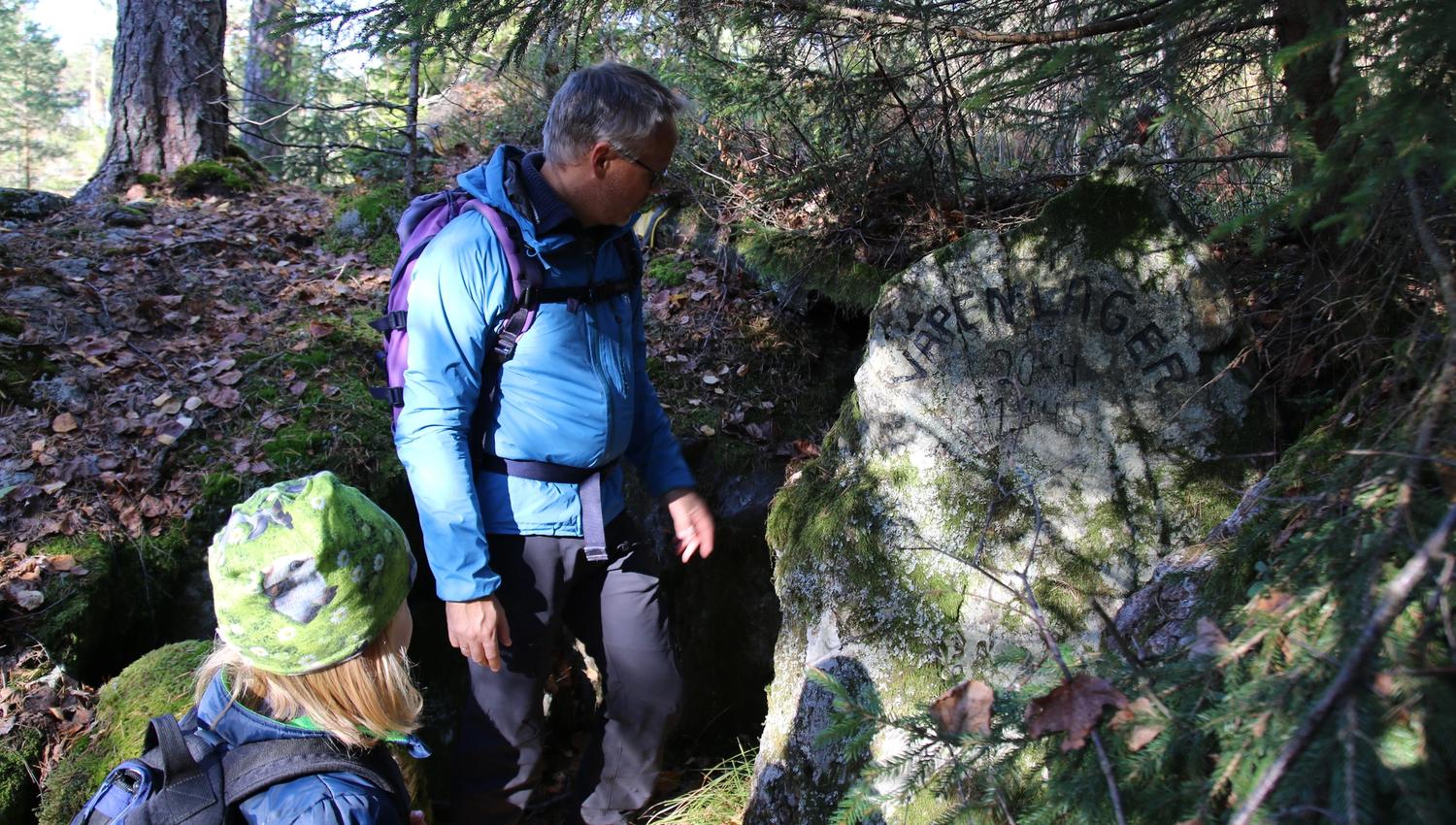 Voksen og barn ser på steinen med innskrift
