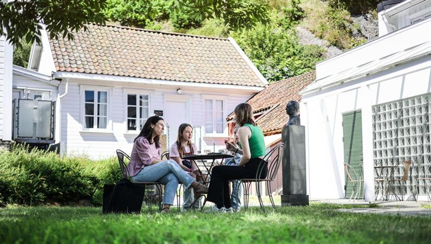 Familie rundt et bord som koser seg med lunsj i hagen