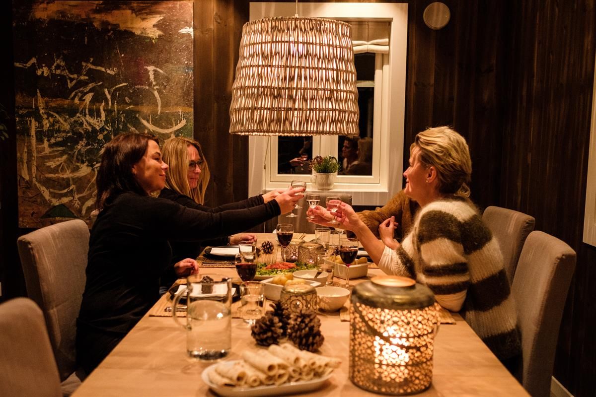 Personer som sitter rundt et spisebord i et varmt belyst rom.