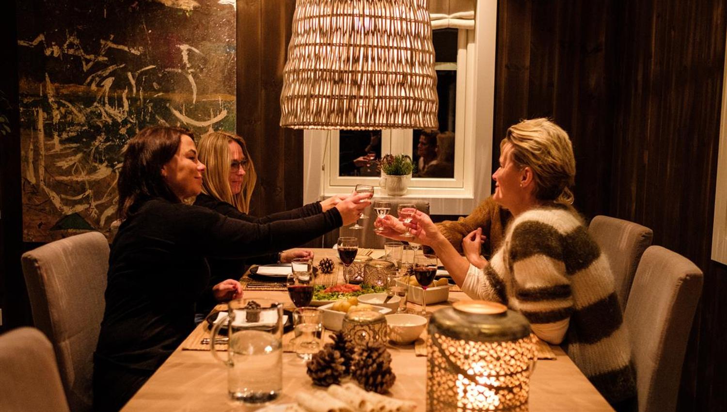Personer som sitter rundt et spisebord i et varmt belyst rom.