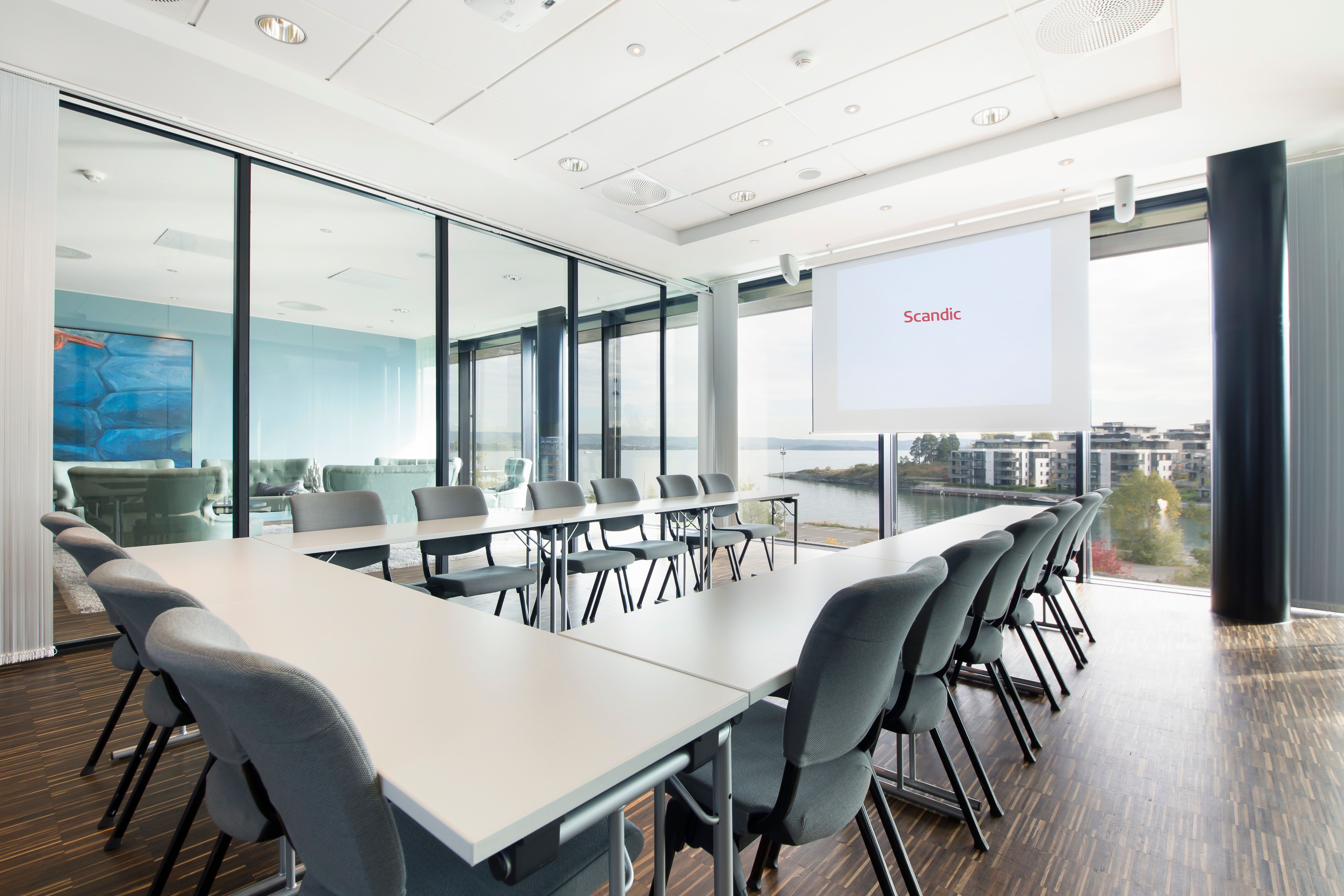 konferansesal med bord i hestesko-oppsett og konferanseteknologi