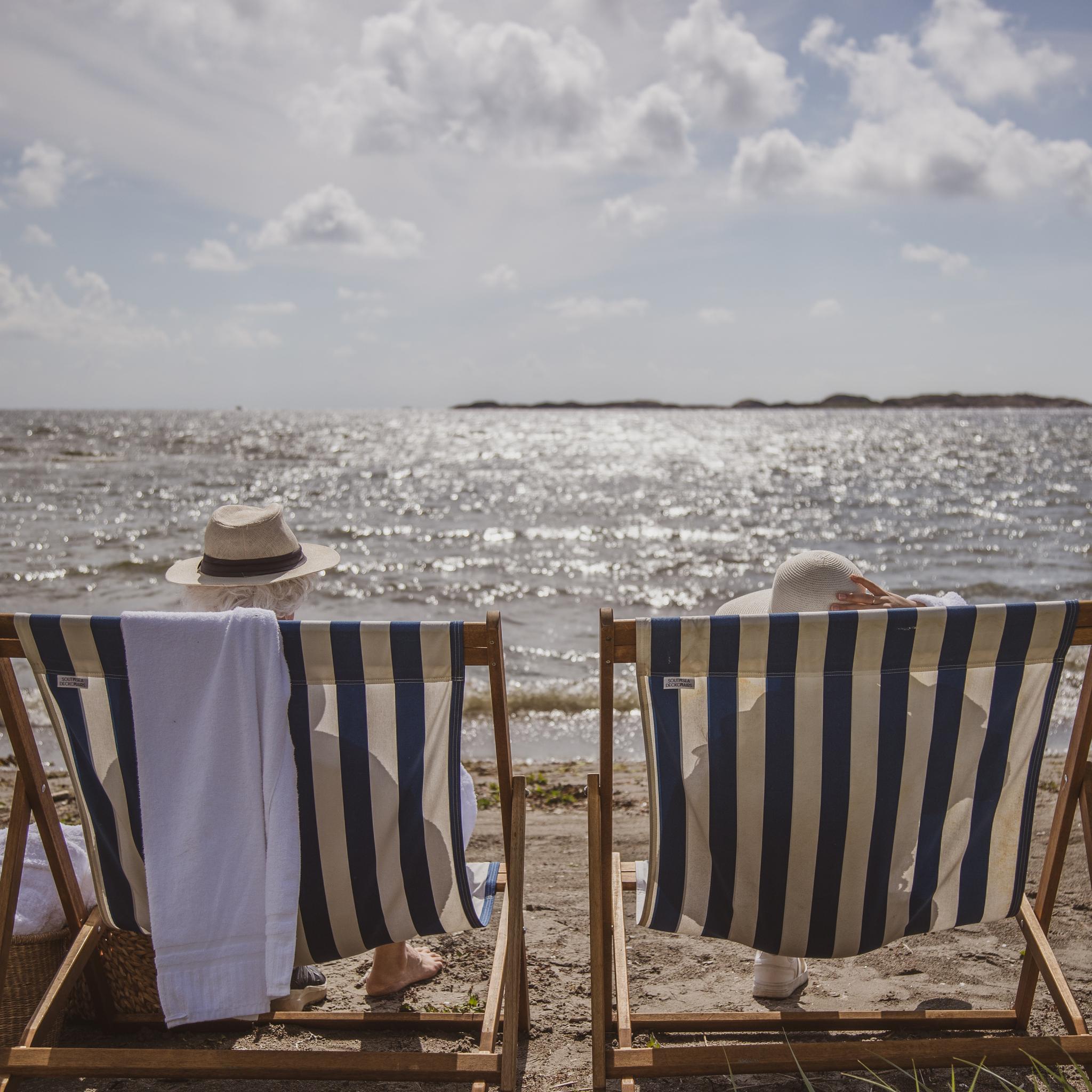 to personer sitter i solstol på strand
