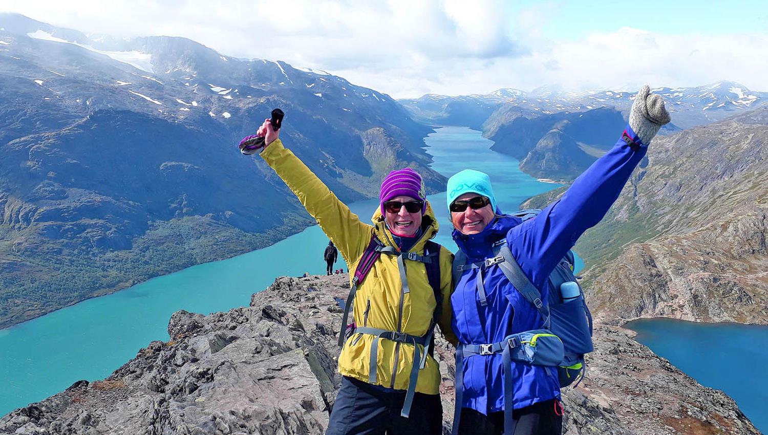 To glade vandrere på en fjellegg med stor utsikt