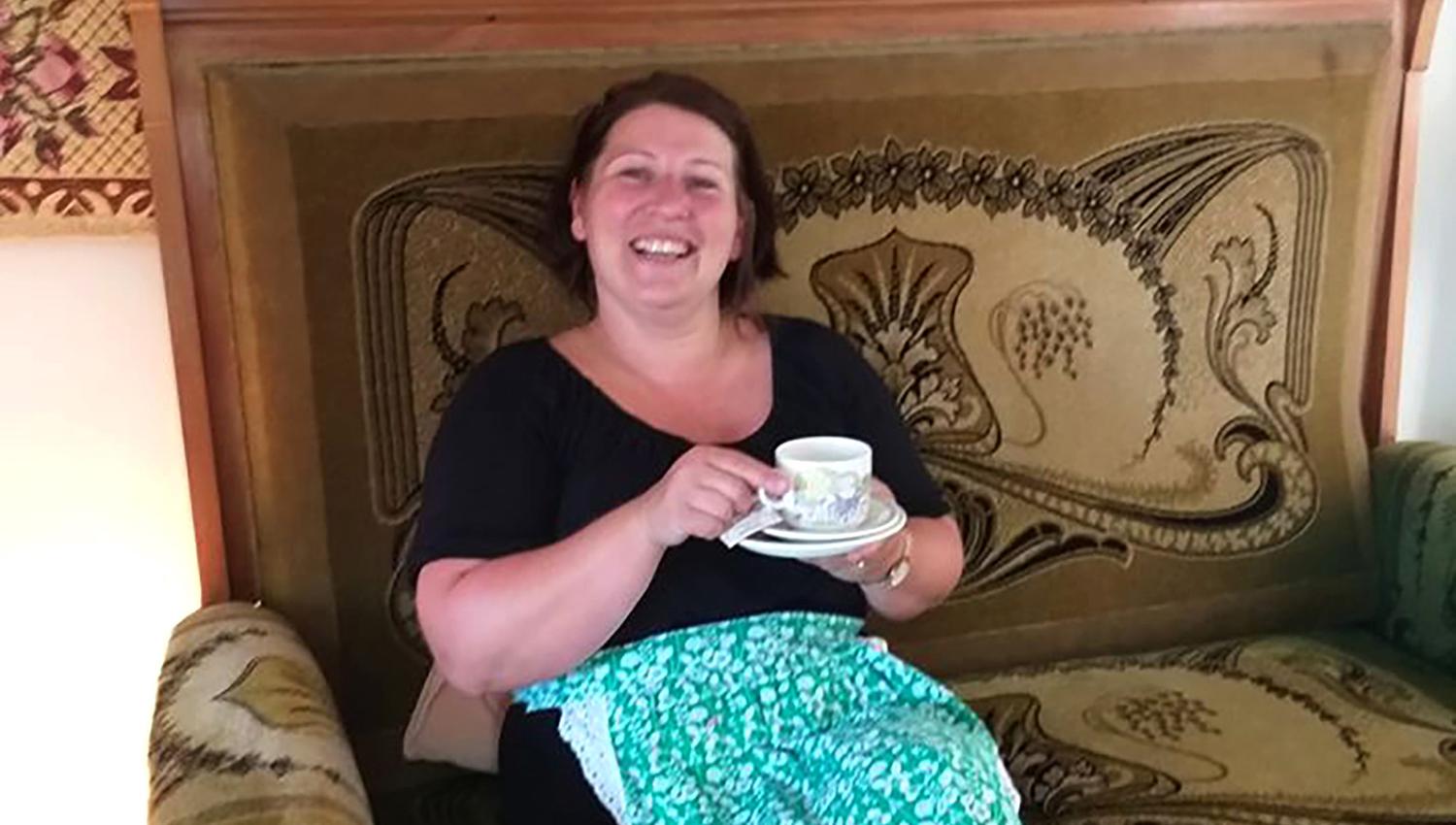 Den ene Kjerringa koser seg med en kopp kaffe i en av sofaene som også er til salgs