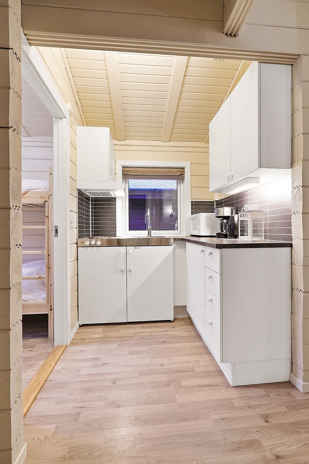 Small modern kitchen with white cabinets, window, and grey tiles