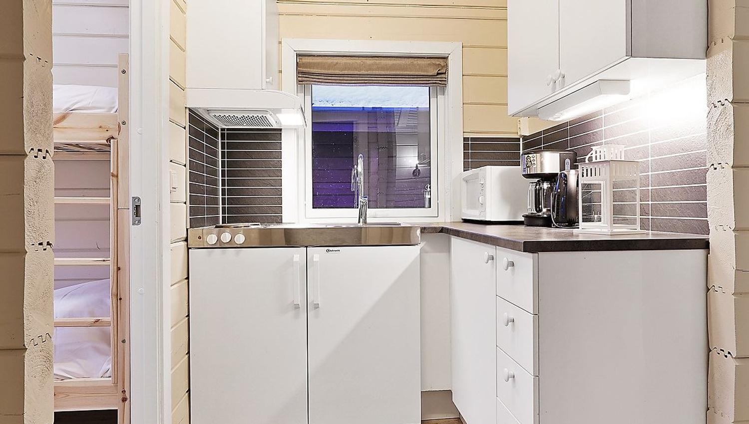 Small modern kitchen with white cabinets, window, and grey tiles