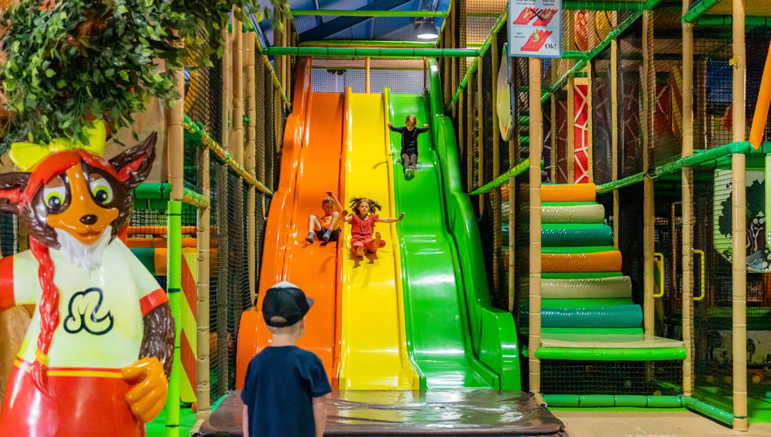 Indoor playground featuring colorful slides and mascots at Mikkelparken