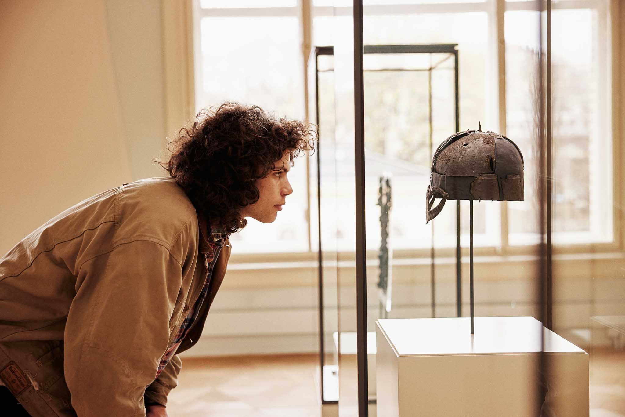 Person studying the viking helmet in a display case