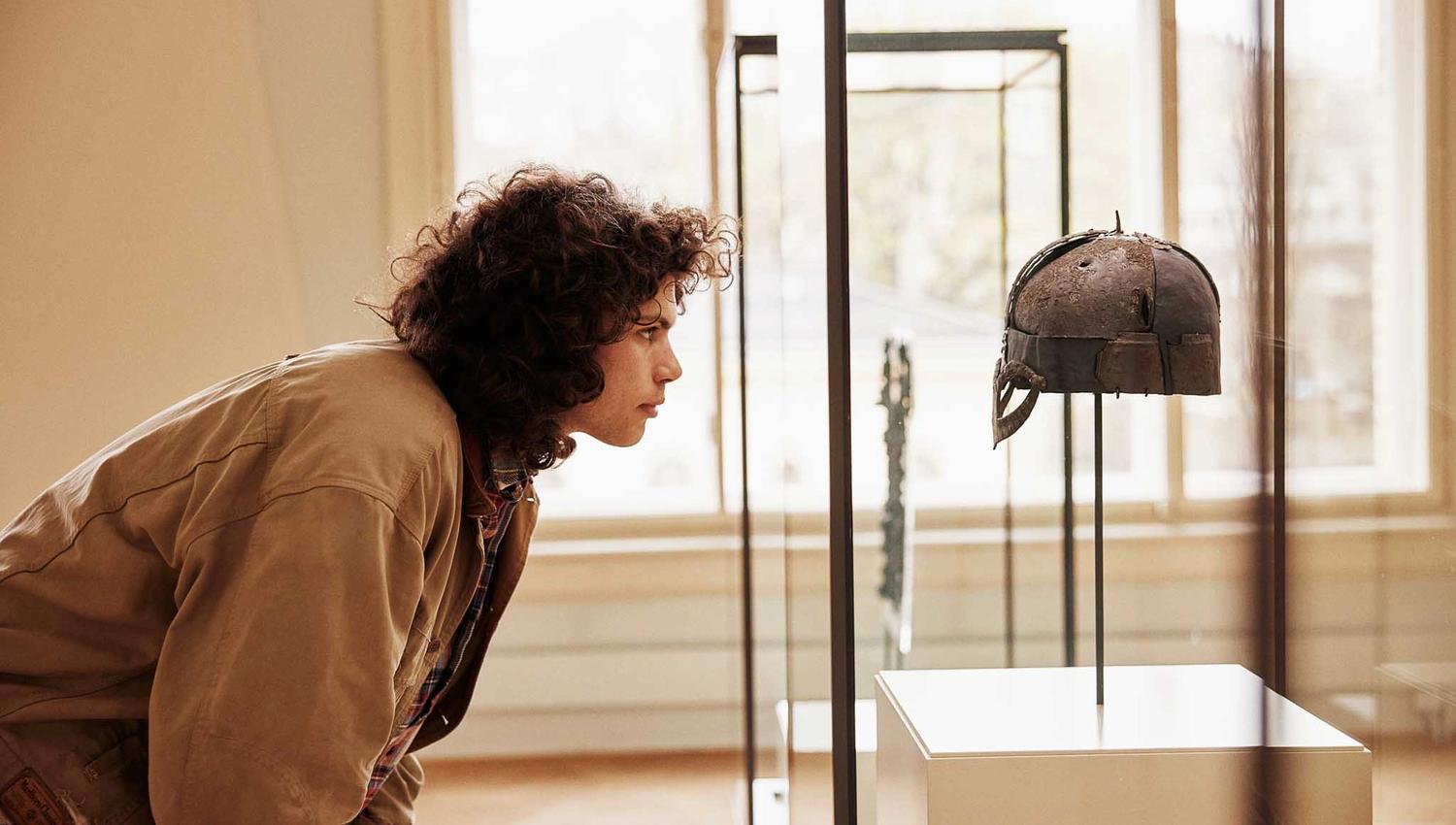 Person studying the viking helmet in a display case