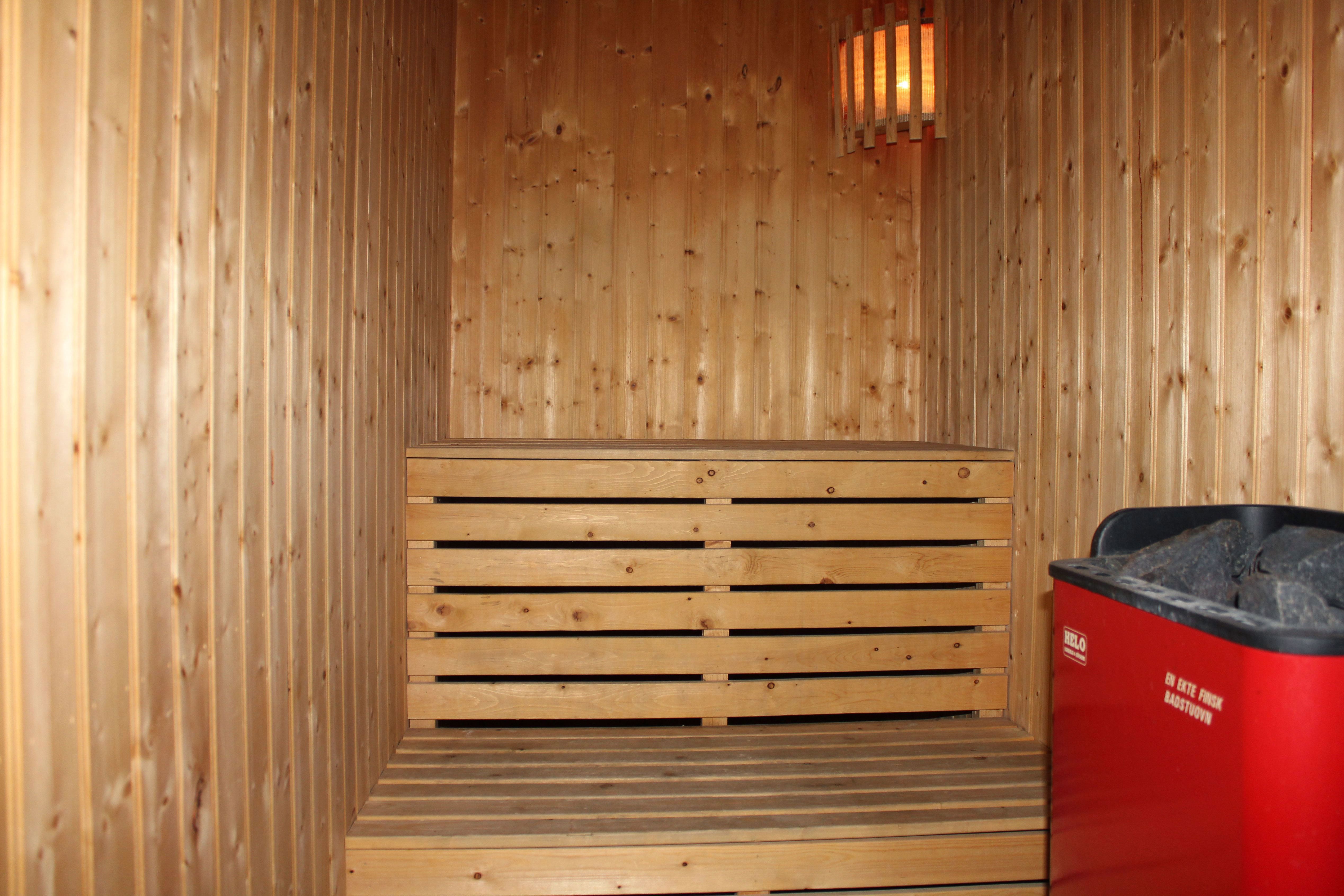 A wooden sauna with a red trash can.