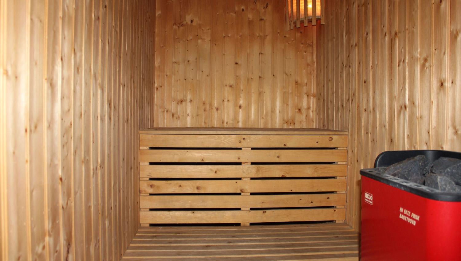 A wooden sauna with a red trash can.
