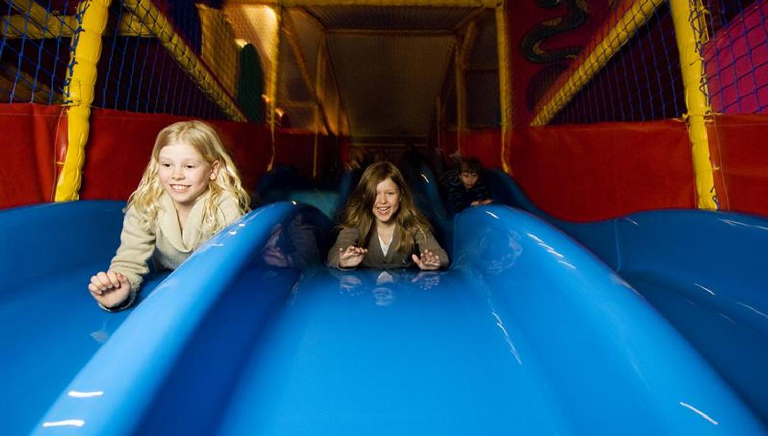 Children slide down on a blue slide.