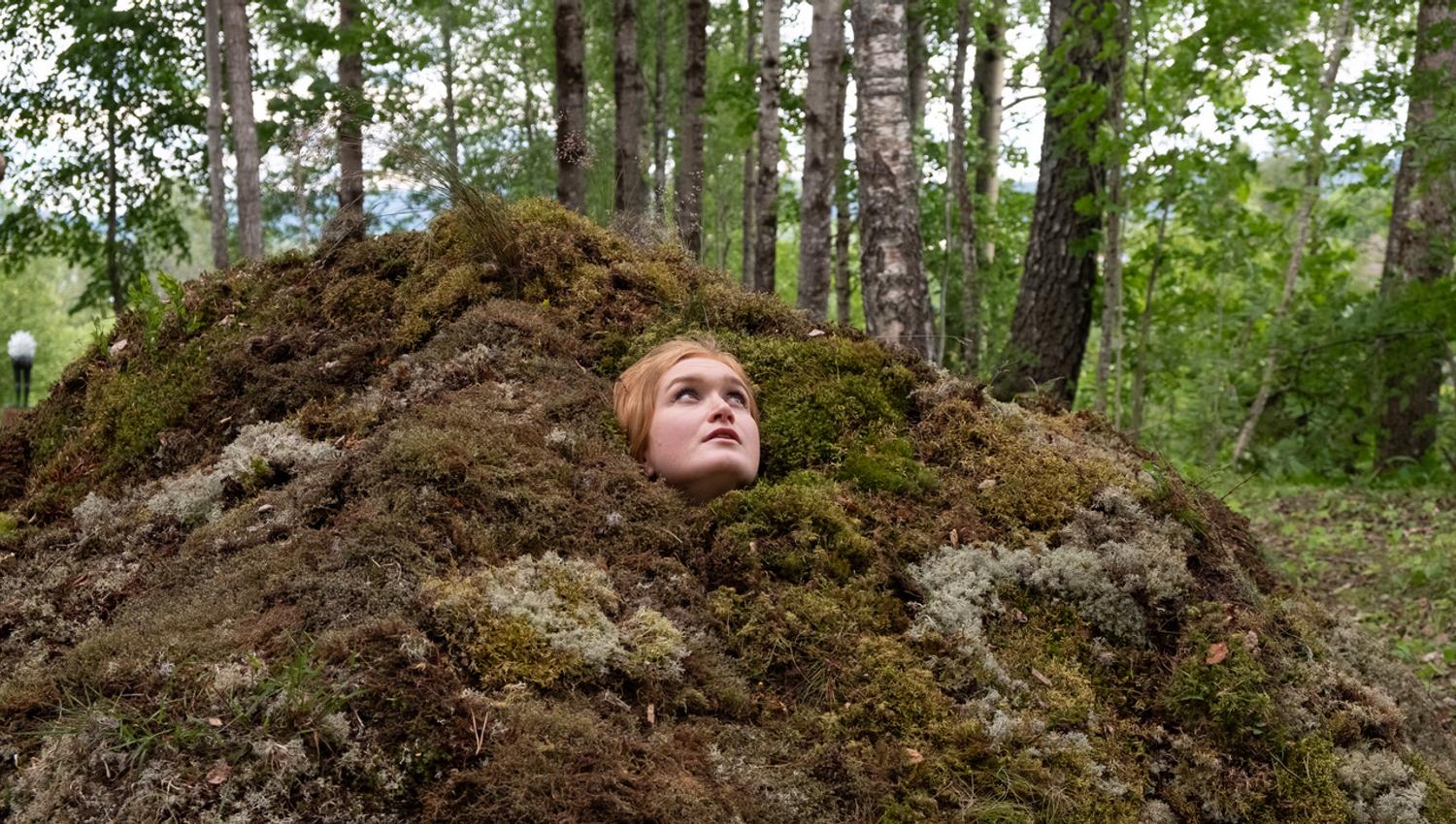 en dame titter frem fra et hull i skogen kunstner Kjersti Austdal : «Tumulus»
