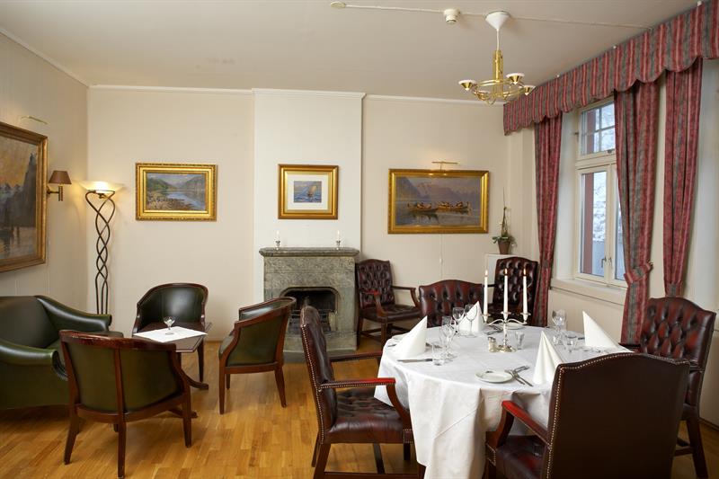 Elegant spisesal med klassiske møblar, peis og ein autentisk atmosfære på Tyssedal Hotel.