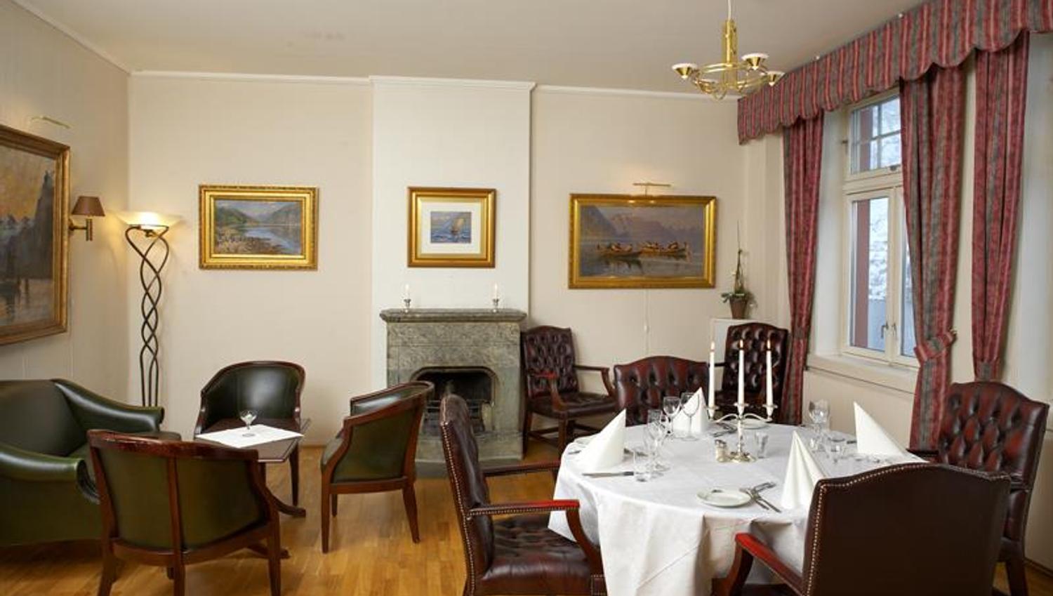 Elegant spisesal med klassiske møblar, peis og ein autentisk atmosfære på Tyssedal Hotel.