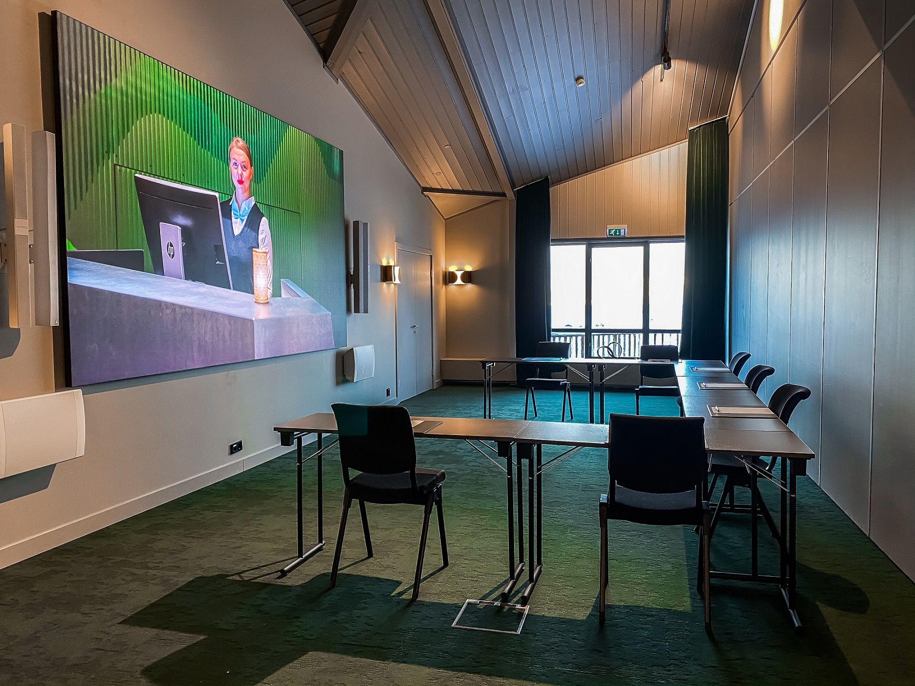 A conference room set up with chairs and tables facing a screen