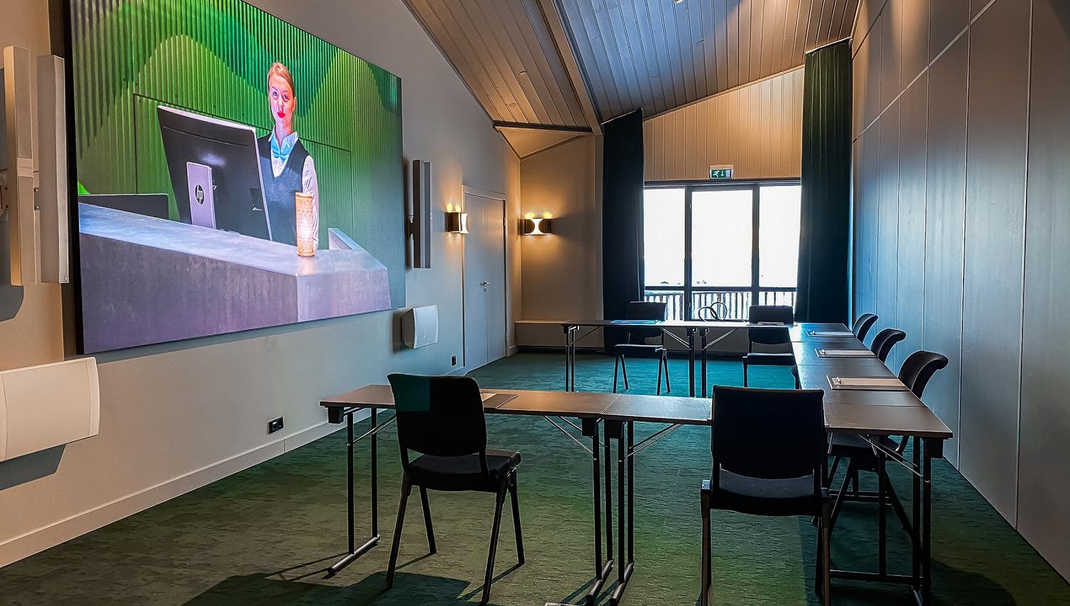 A conference room set up with chairs and tables facing a screen