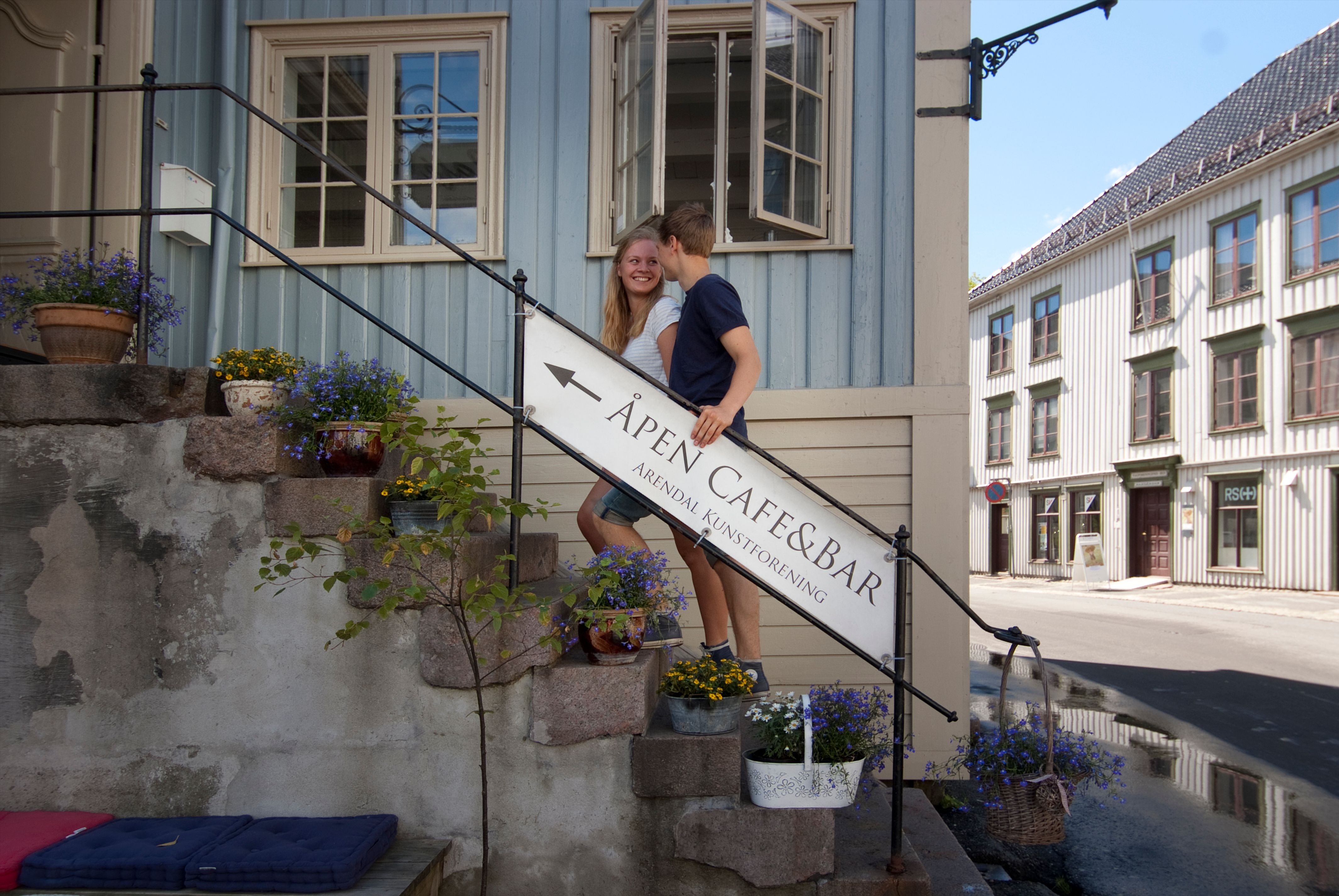 ungt par i trappa opp til Det Lindvedkse hus på Nedre Tyholmen. Gammelt trehus i rokokostil med lyseblå stående panel og imitert marmor på tversbjelker.