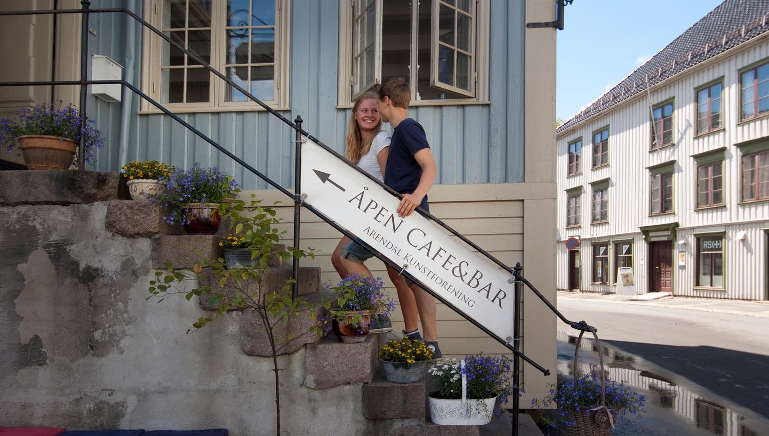 ungt par i trappa opp til Det Lindvedkse hus på Nedre Tyholmen. Gammelt trehus i rokokostil med lyseblå stående panel og imitert marmor på tversbjelker.