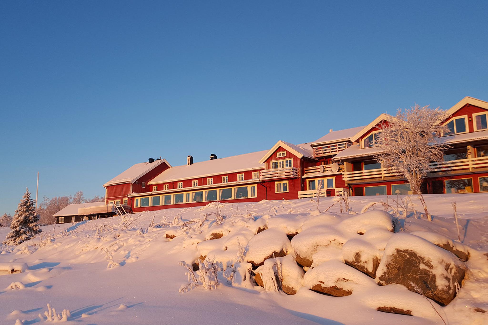A red wooden hotel in snowclad landscape and warm winter light