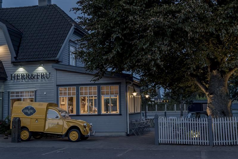 Fasade på kveldstid: grå restaurant. Gul leveringsbil parkert ved restauranten.