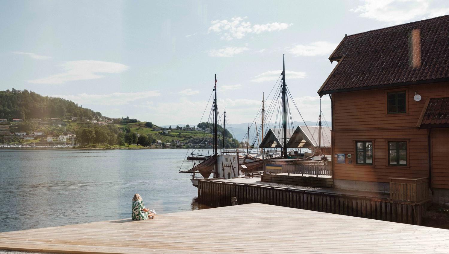 Peaceful moment by the fjord at the Hardanger Maritime Centre, overlooking historic boats and boathouses.