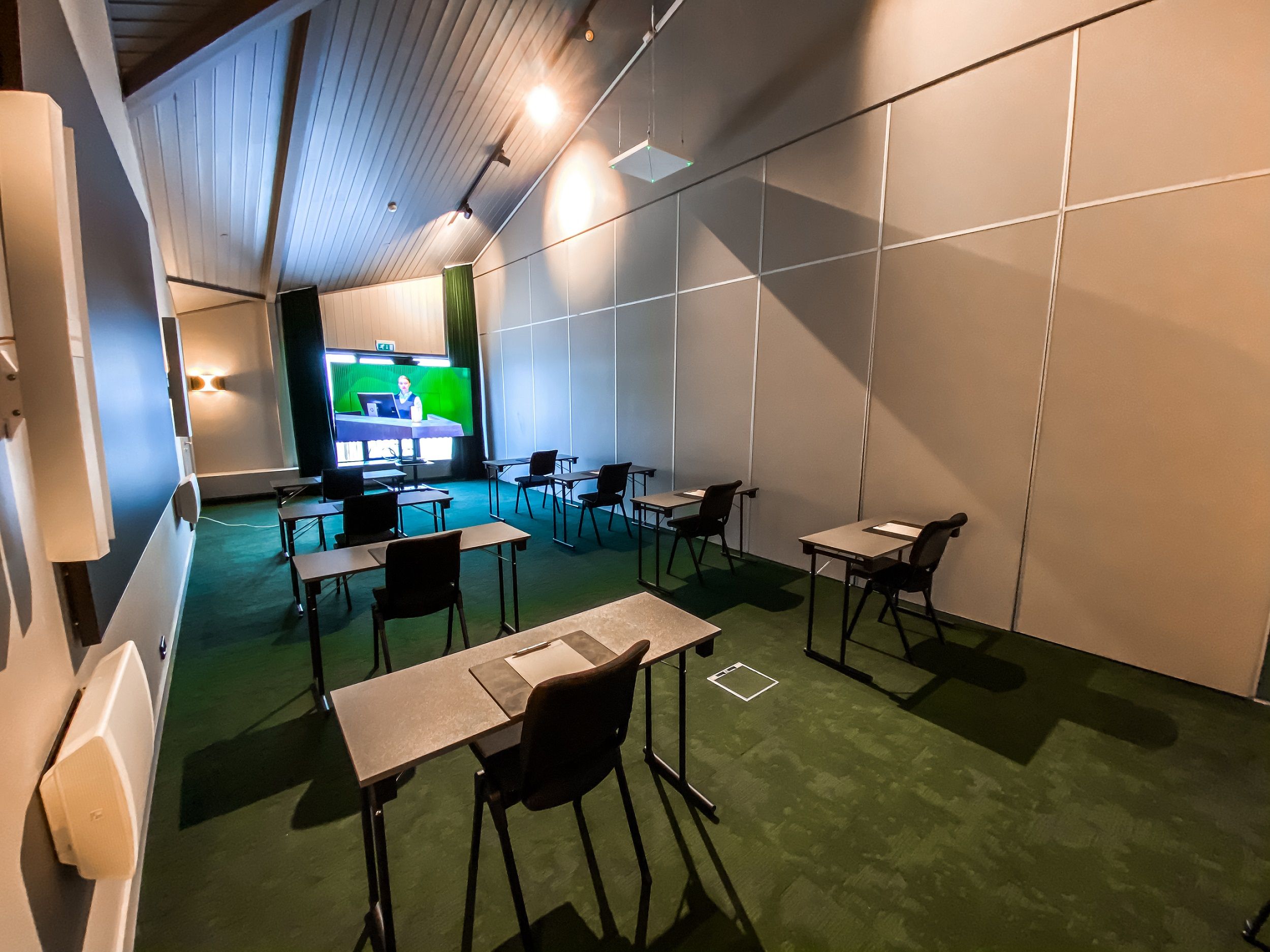 A conference room set up with chairs and tables facing a screen