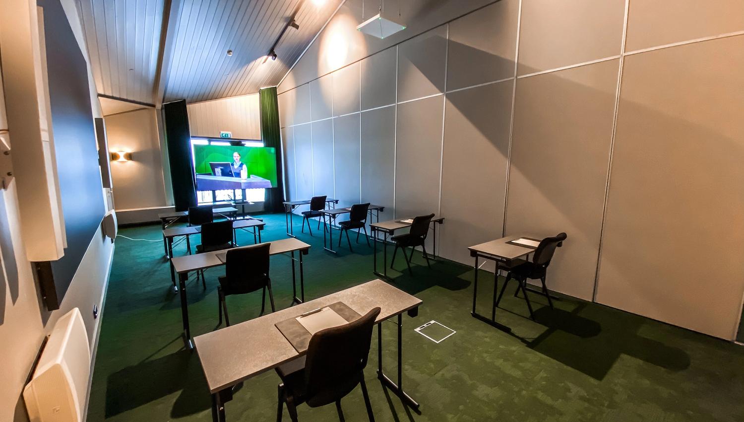 A conference room set up with chairs and tables facing a screen
