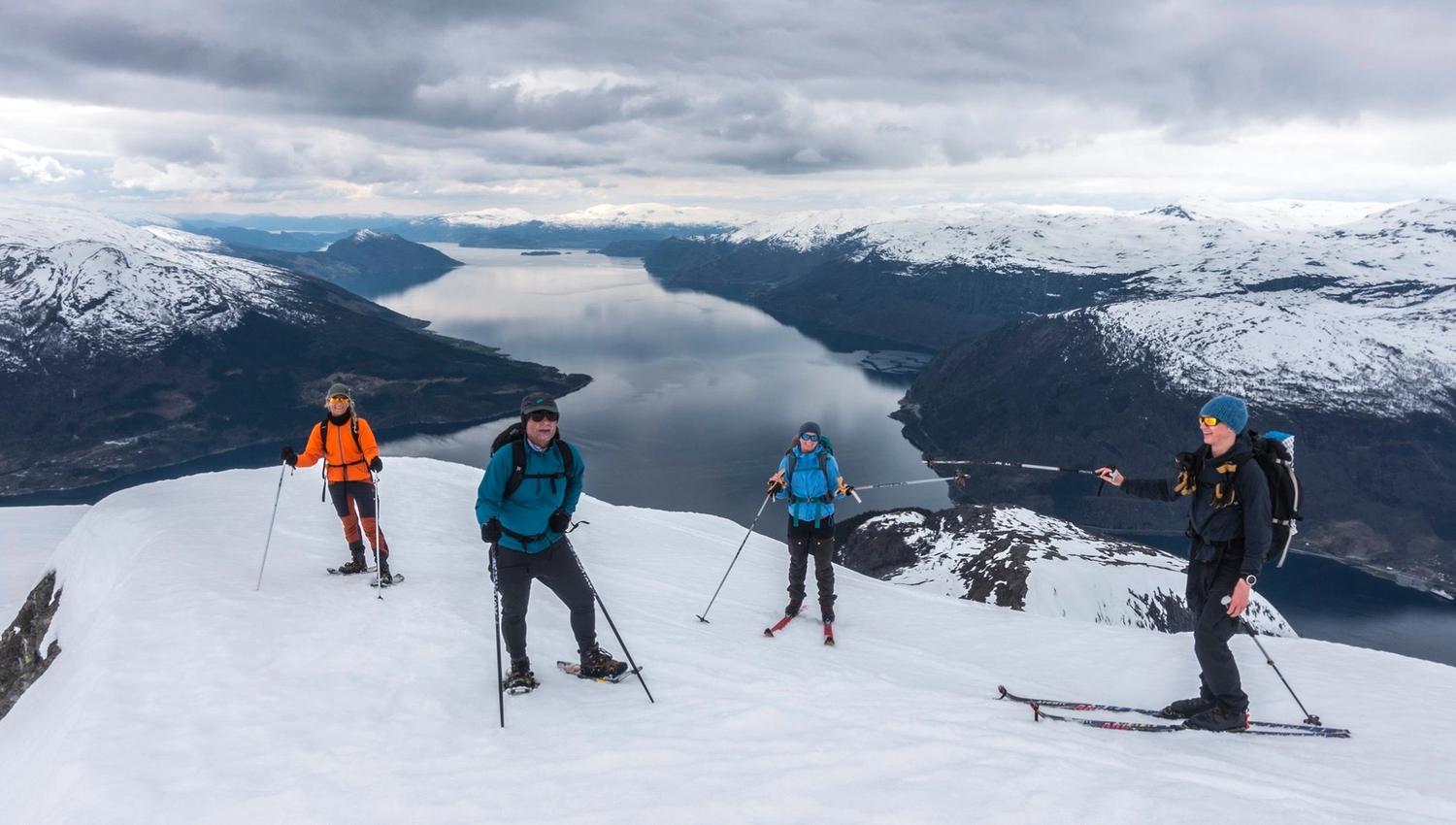 Group snowshoeing across snowy mountains with views of the Hardangerfjord below.