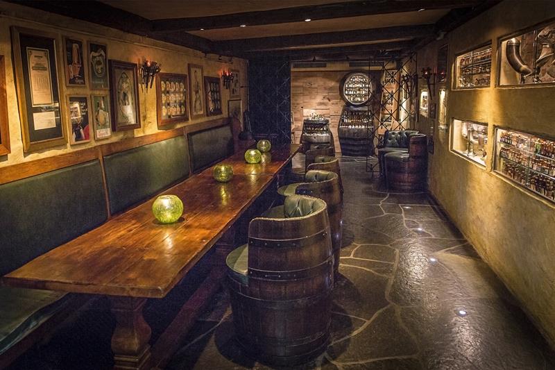 Sitteseksjon, langbord i tre, stoler laget av tønner og utstilte småflasker