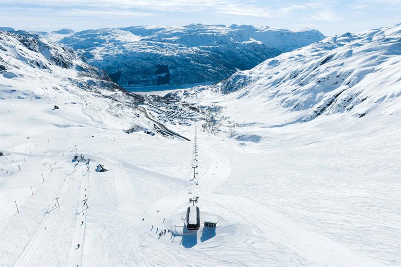 View from Røldal Ski Resort down towards the fjord and village surrounded by winter scenery.