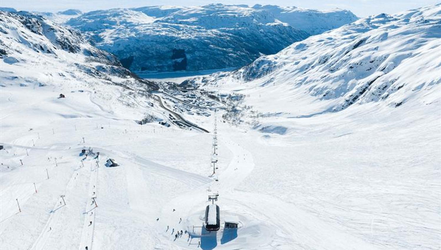 View from Røldal Ski Resort down towards the fjord and village surrounded by winter scenery.