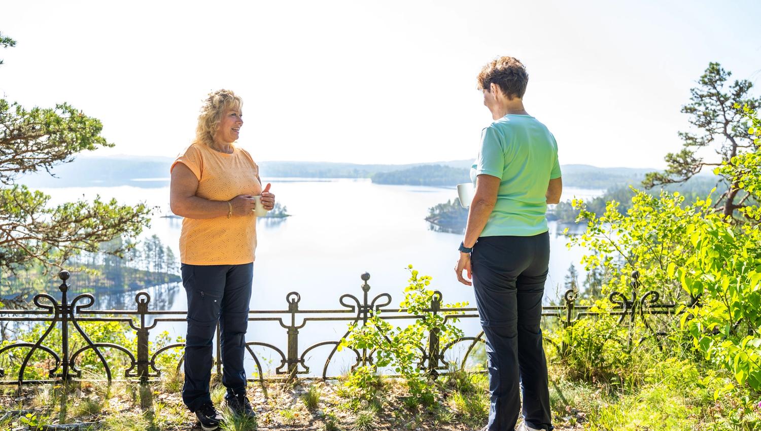 Damer som snakker foran sjøutsikt