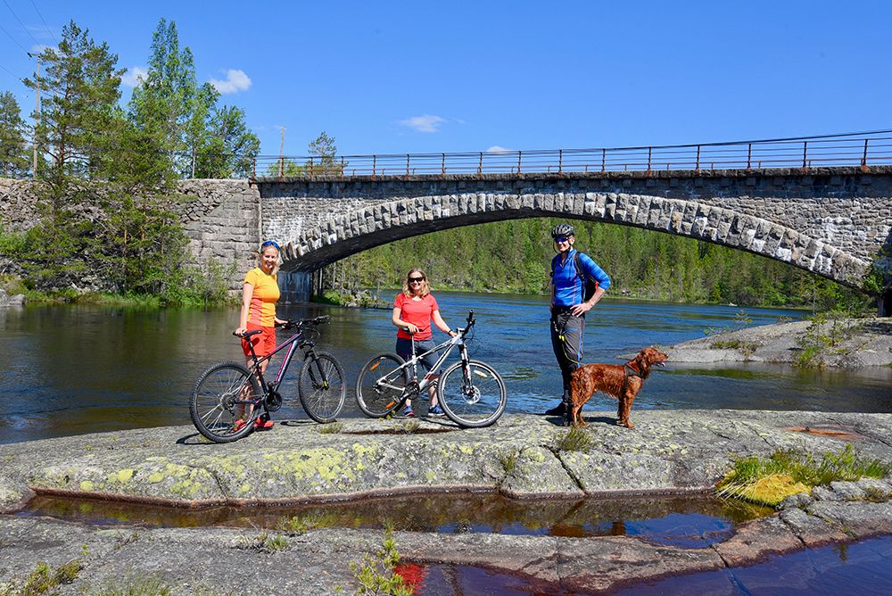 syklister tar en pause på en svaberg ved elva langs sykkelveien "gamle Treungenbanen"