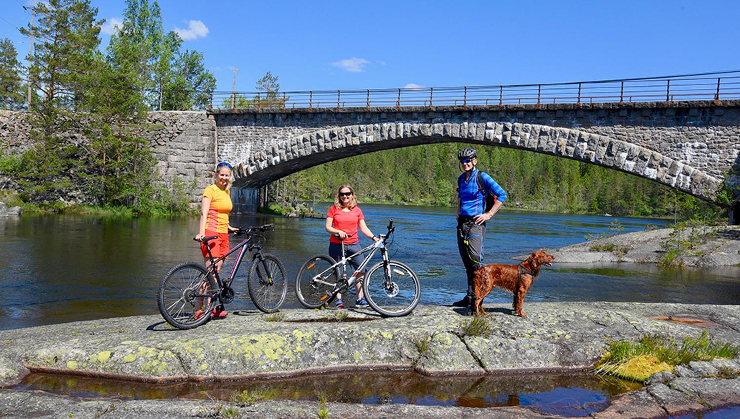 syklister tar en pause på en svaberg ved elva langs sykkelveien "gamle Treungenbanen"