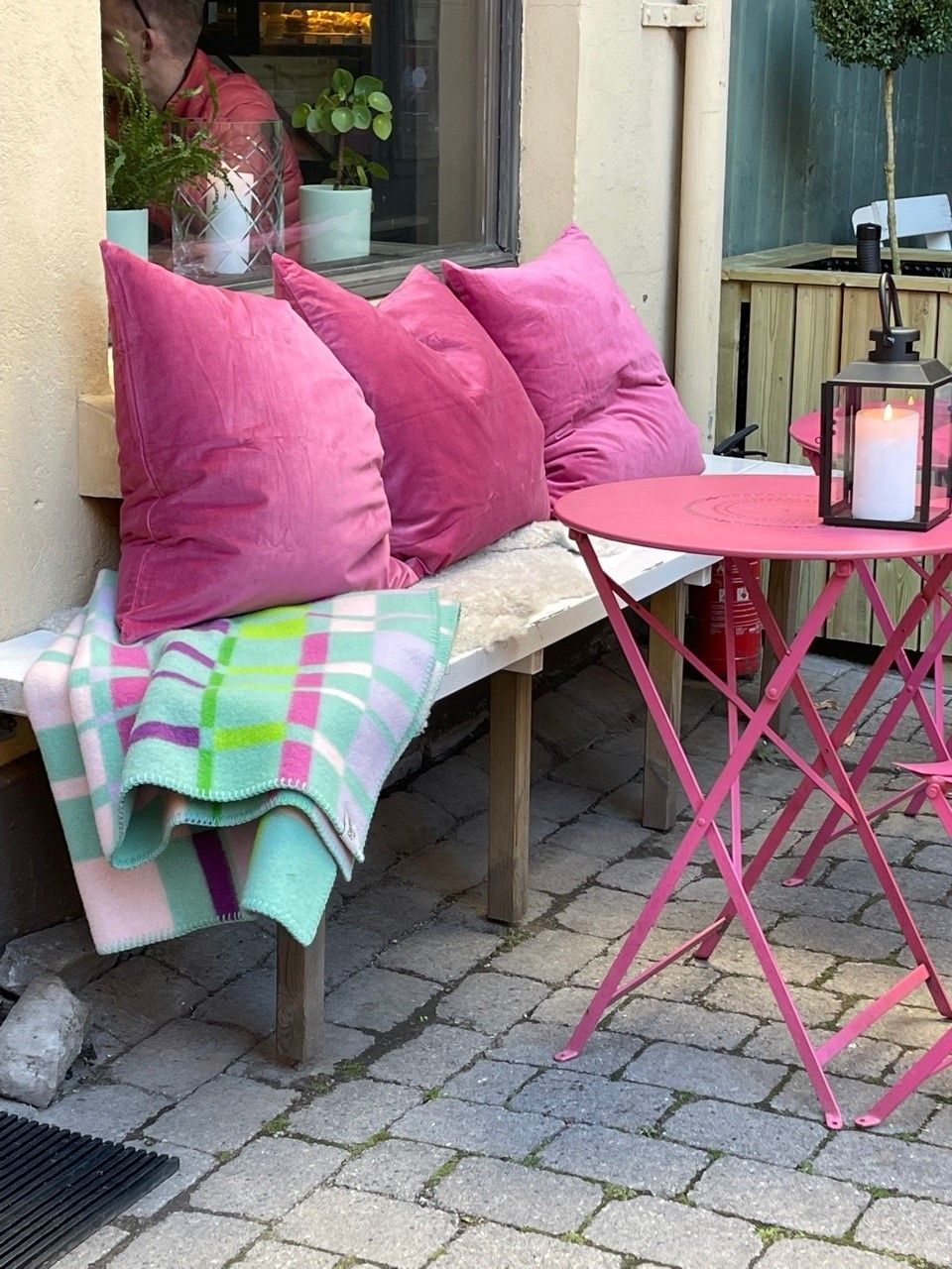 Benk med rosa bord, rosa puter og pledd