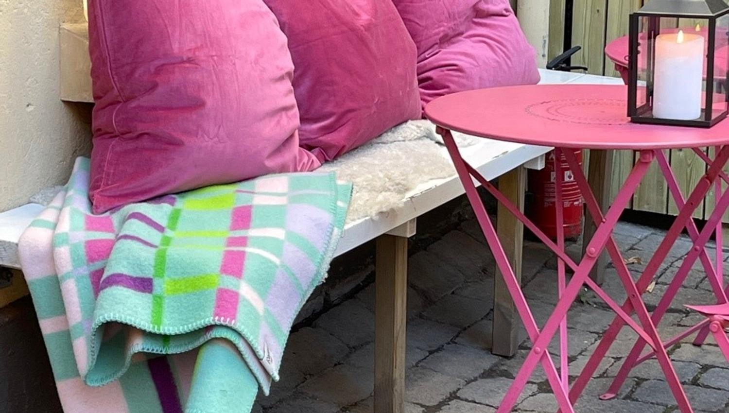 Benk med rosa bord, rosa puter og pledd