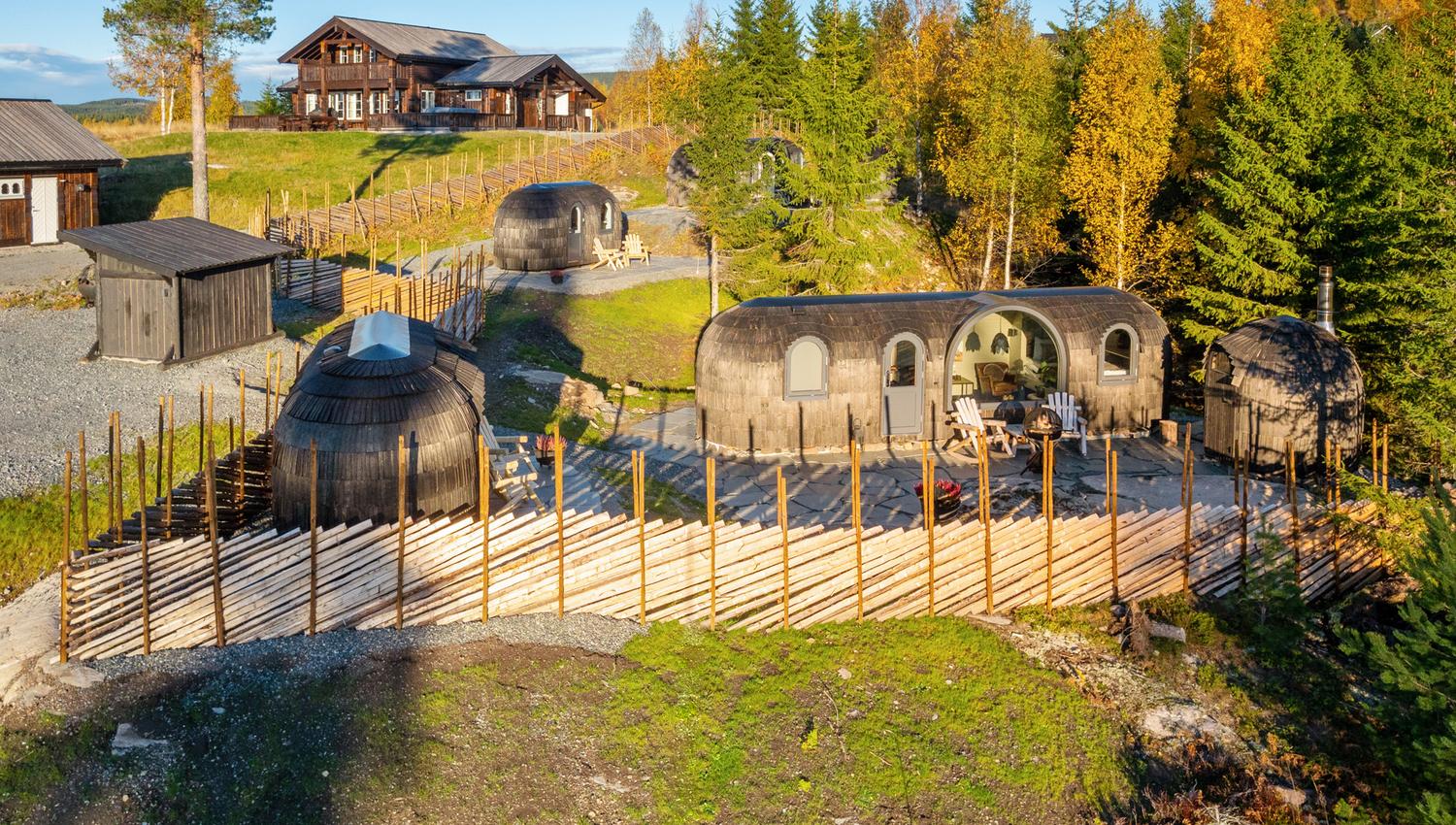 dronebilde av hytter med et gjerde og skog rundt