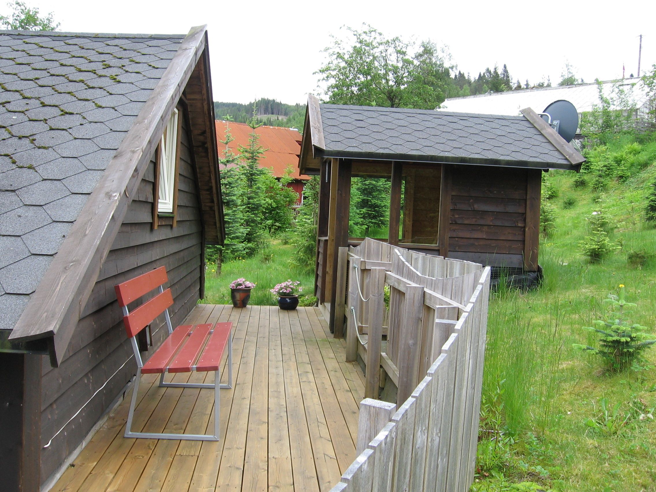 Hyggelig uteplass med treterrasse, benk og blomstrar ved Vågen Rom og Hytteutleige i Hardanger.