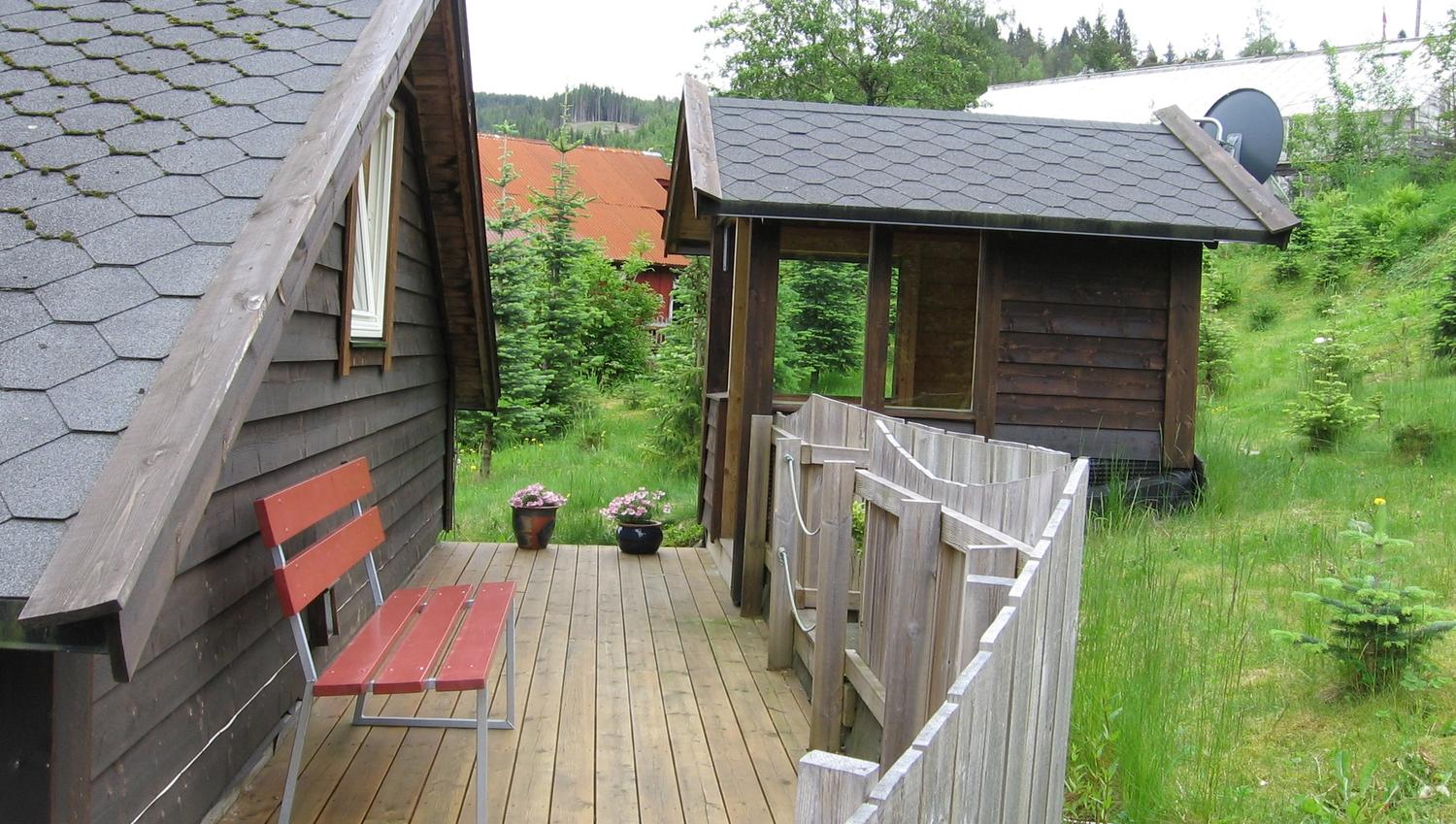 Hyggelig uteplass med treterrasse, benk og blomstrar ved Vågen Rom og Hytteutleige i Hardanger.