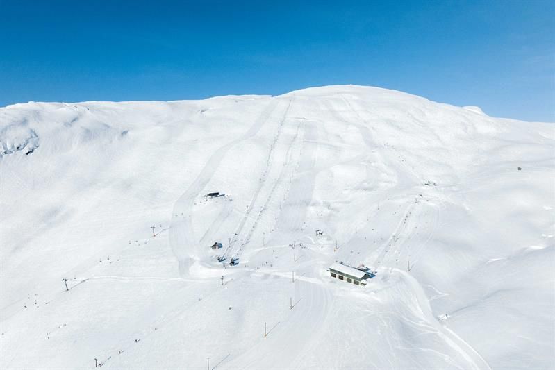 Groomed ski slopes and lifts at Røldal Ski Resort under a blue sky and sparkling snow.